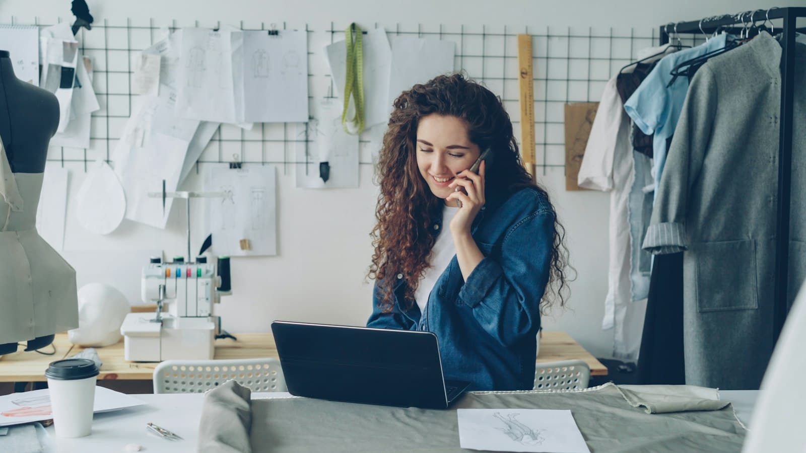 Fashion designer on the phone, working on a laptop